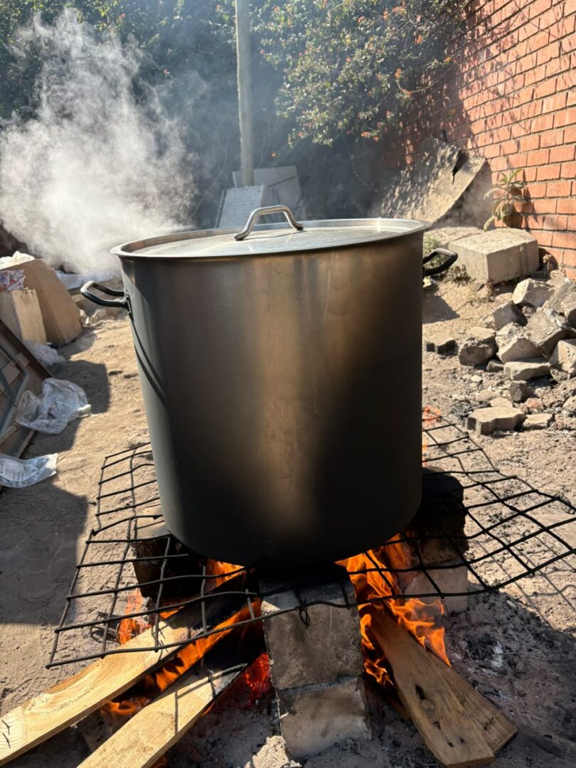 A large pot of food cooking over an open fire at Omosa Development.