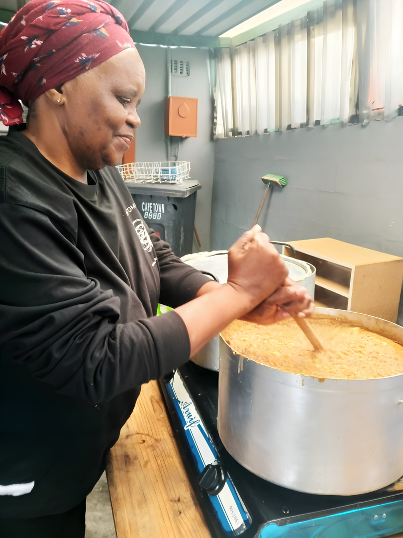 A community kitchen volunteer preparing a large pot of cooked food at Give Food Solutions, a SA Harvest beneficiary organisation that provides meals and community support programmes in Cape Town.